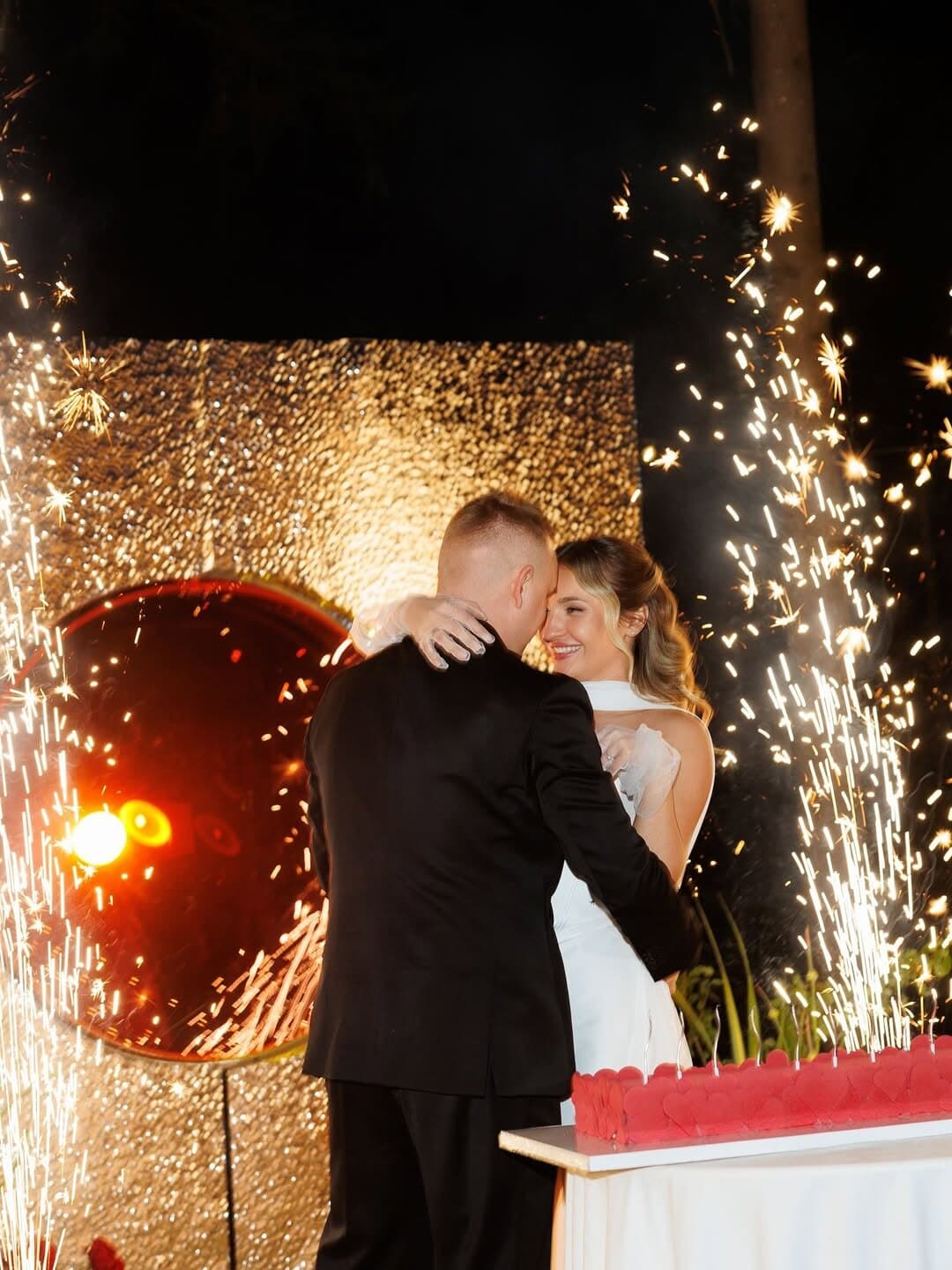 Couple embracing on the dance floor beside a cold spark fountain throwing sparks into the air