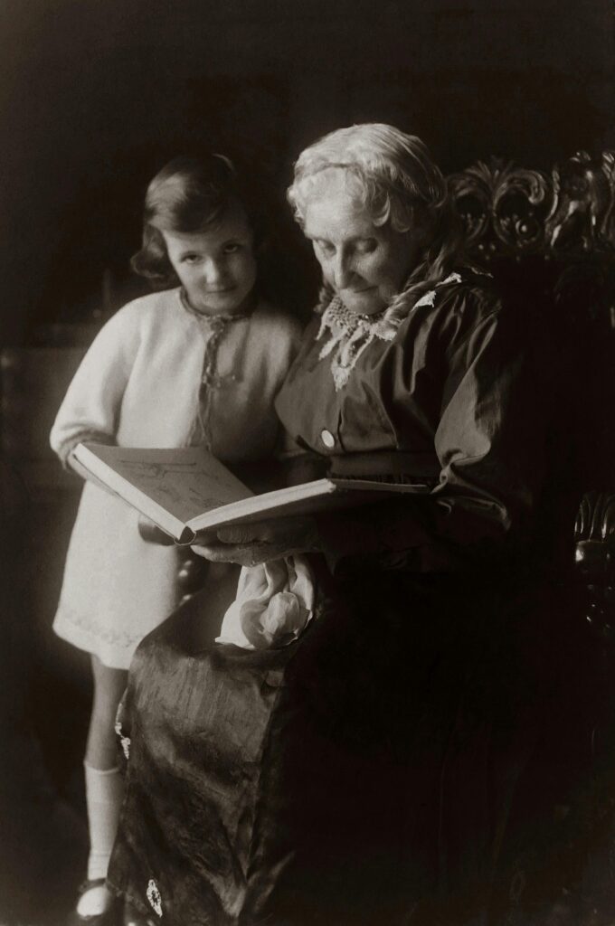 A heartwarming vintage photo of a grandmother reading to her granddaughter.